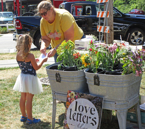 A women sharing information about flowers to a young girl during the open market event